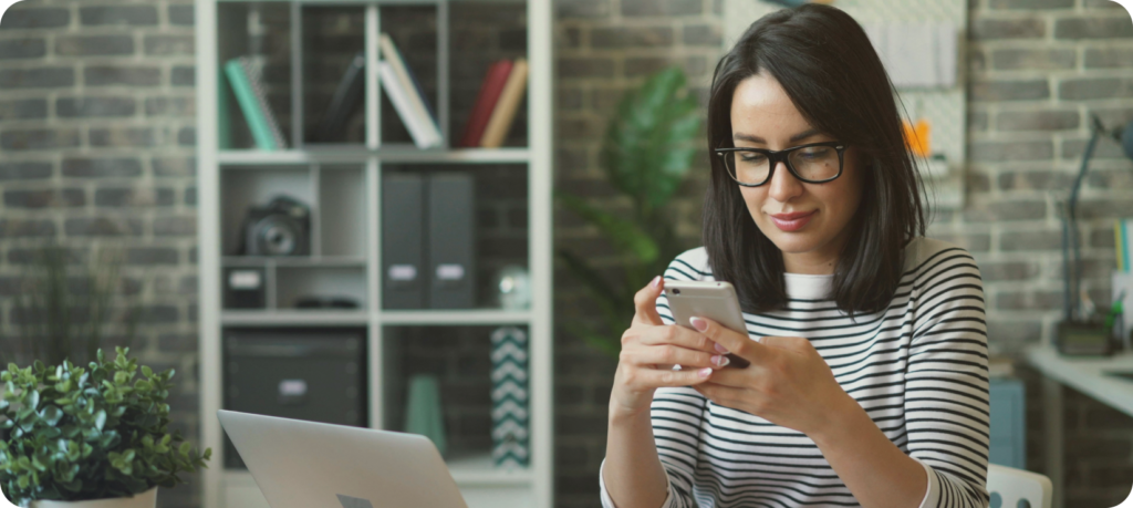 Femme qui regarde son smartphone et qui se renseigne sur le virement Open Banking